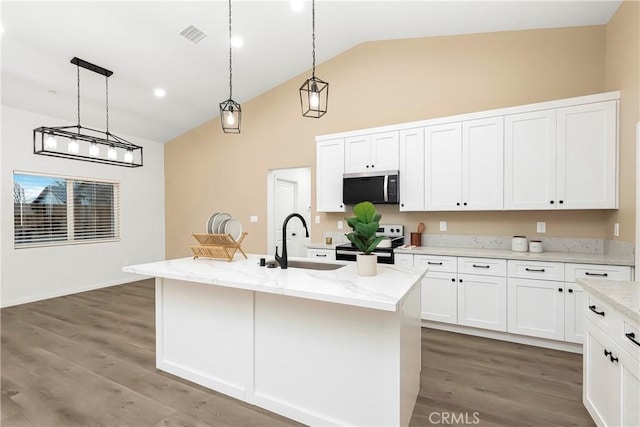 kitchen with electric stove, stainless steel microwave, white cabinets, a sink, and wood finished floors