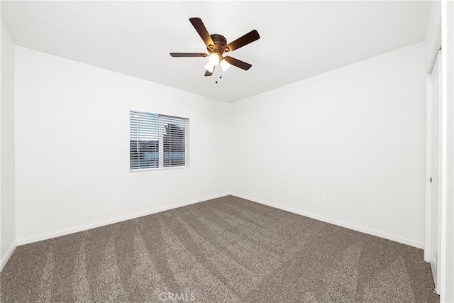 unfurnished room featuring dark colored carpet, ceiling fan, and baseboards