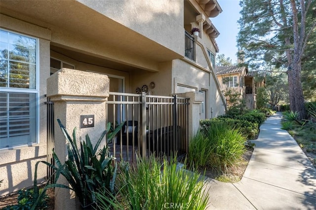 view of side of home with stucco siding and fence