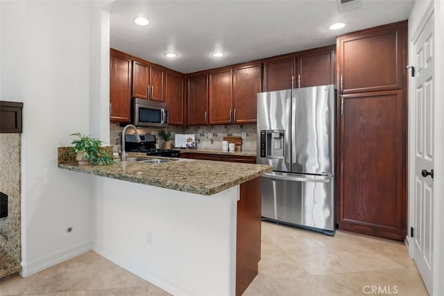 kitchen with light stone counters, decorative backsplash, recessed lighting, a peninsula, and stainless steel appliances