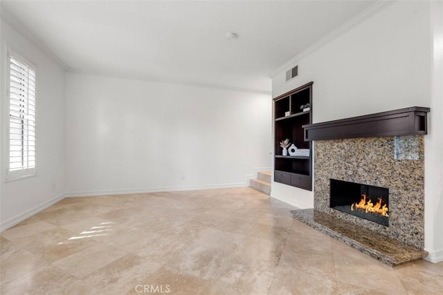 unfurnished living room with built in features, visible vents, baseboards, a fireplace, and ornamental molding