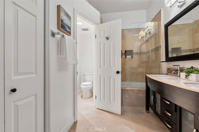 bathroom featuring tiled shower / bath, visible vents, toilet, a sink, and double vanity