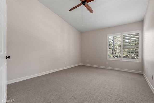 carpeted spare room featuring lofted ceiling, a ceiling fan, and baseboards