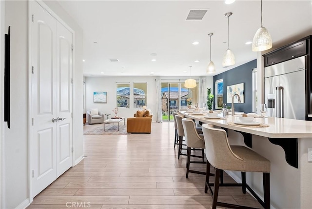 kitchen with light countertops, light wood-type flooring, a kitchen bar, and visible vents