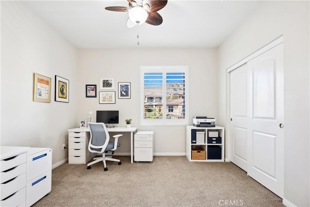 office area featuring light carpet, ceiling fan, and baseboards