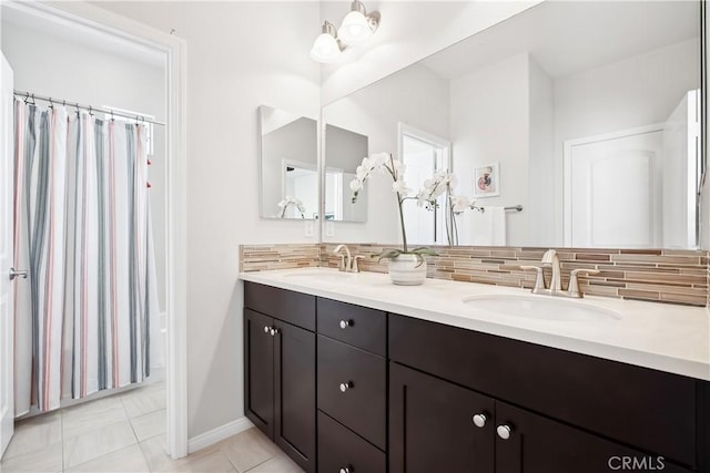 bathroom featuring tasteful backsplash, tile patterned flooring, a sink, and double vanity