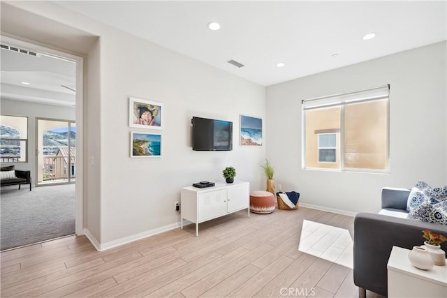 living room featuring light wood-style floors, recessed lighting, visible vents, and baseboards