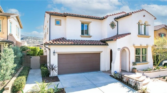 mediterranean / spanish-style house with an attached garage, a tile roof, concrete driveway, and stucco siding