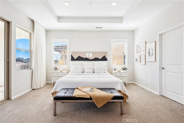 bedroom with light carpet, visible vents, and a raised ceiling