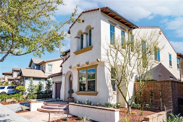 mediterranean / spanish-style home featuring concrete driveway, a tile roof, and stucco siding