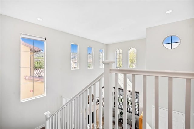 hall featuring a healthy amount of sunlight, an upstairs landing, and recessed lighting