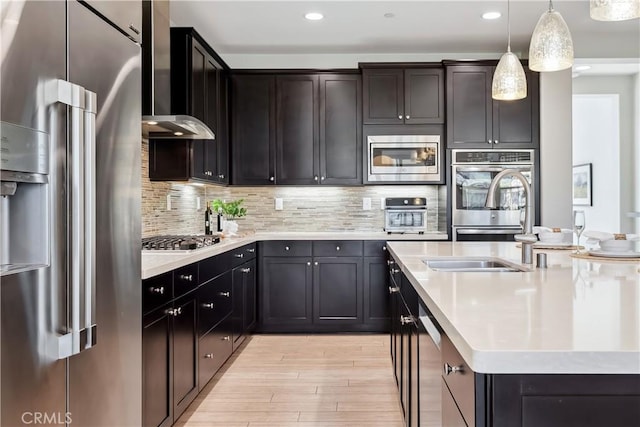 kitchen with appliances with stainless steel finishes, light countertops, backsplash, and an island with sink