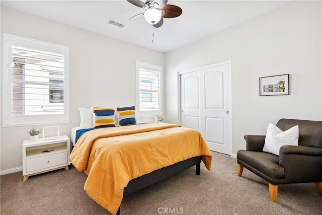 carpeted bedroom featuring ceiling fan, a closet, visible vents, and baseboards