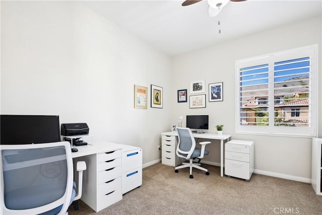 office space featuring light carpet, baseboards, and a ceiling fan