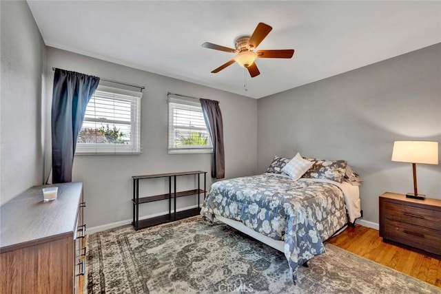 bedroom with ceiling fan, wood finished floors, and baseboards