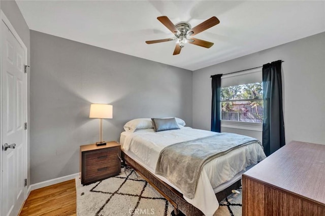 bedroom featuring light wood finished floors, ceiling fan, and baseboards