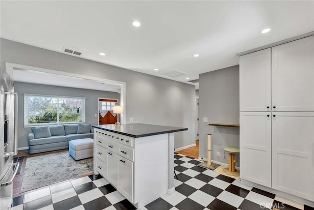 kitchen with visible vents, white cabinets, open floor plan, light floors, and dark countertops