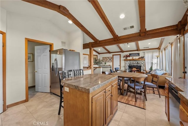 kitchen with visible vents, appliances with stainless steel finishes, a center island, a kitchen bar, and beam ceiling