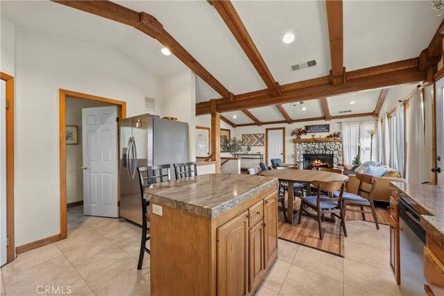 820 Arbula Dr, Crestline, CA 92325 - kitchen with a center island, vaulted ceiling with beams, stainless steel appliances, a fireplace, and a kitchen bar