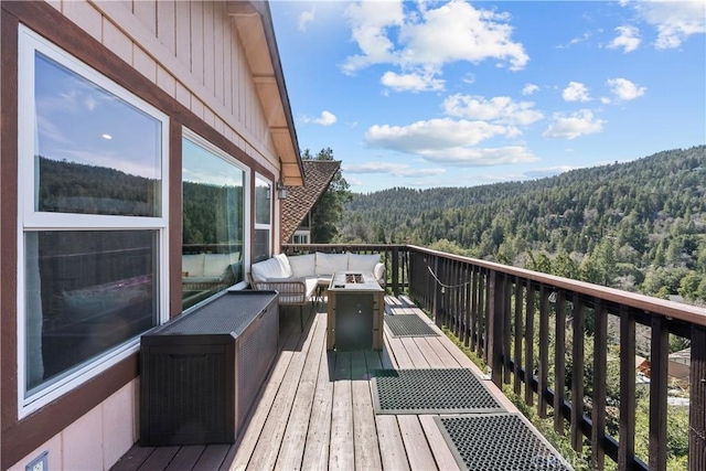 wooden terrace featuring an outdoor hangout area and a wooded view