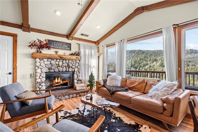 820 Arbula Dr, Crestline, CA 92325 - living area with wood finished floors, vaulted ceiling with beams, a fireplace, a forest view, and visible vents