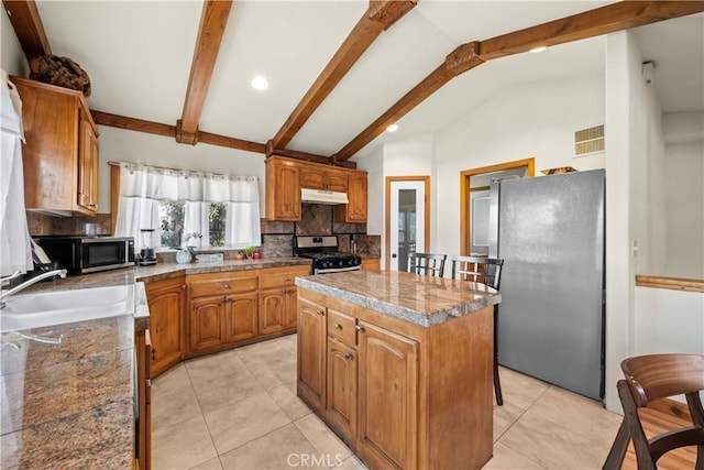 kitchen featuring under cabinet range hood, a kitchen island, a sink, appliances with stainless steel finishes, and decorative backsplash