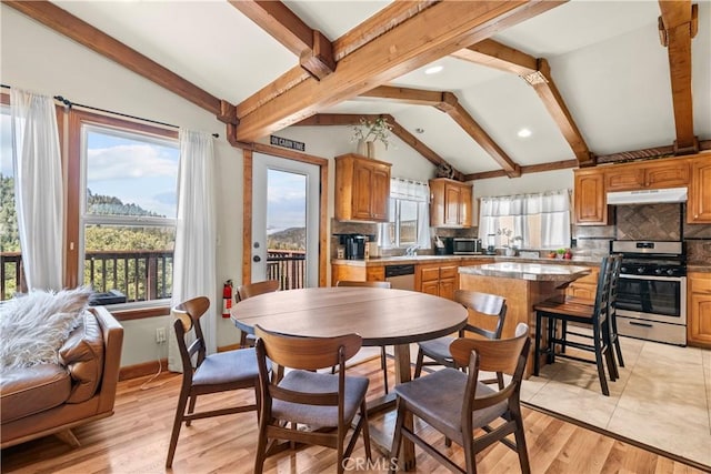 dining room with vaulted ceiling with beams, light wood-style flooring, and baseboards