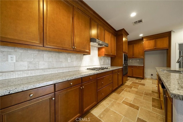 kitchen featuring stainless steel gas cooktop, stone tile floors, visible vents, oven, and under cabinet range hood