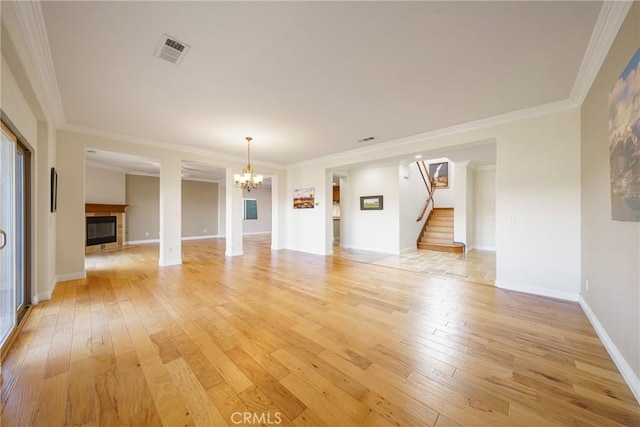 unfurnished living room featuring stairs, visible vents, an inviting chandelier, light wood-type flooring, and a tile fireplace