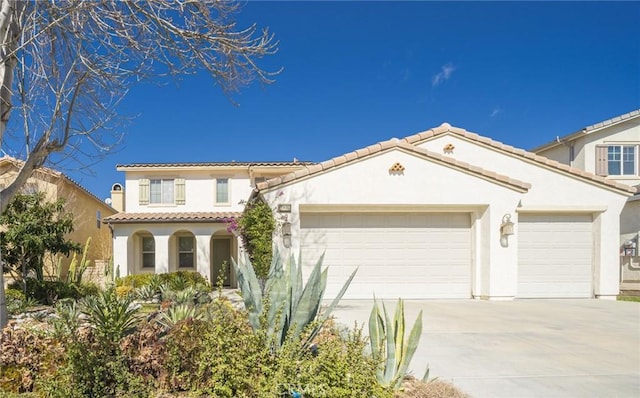 mediterranean / spanish home with a garage, driveway, a tiled roof, and stucco siding