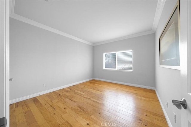 empty room featuring light wood finished floors, baseboards, and ornamental molding