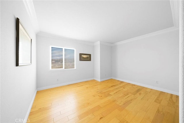 empty room featuring ornamental molding, light wood-style flooring, and baseboards