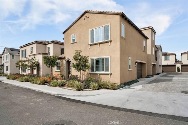 view of property exterior featuring a garage, driveway, a tiled roof, and stucco siding