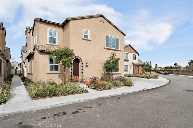 mediterranean / spanish home with fence, a tiled roof, and stucco siding