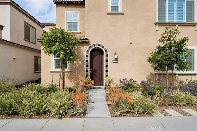 property entrance featuring a tiled roof and stucco siding