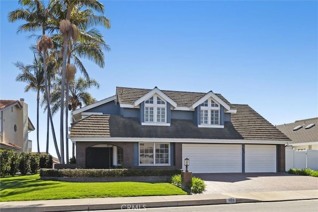 view of front of property with a front yard, decorative driveway, a tile roof, and fence