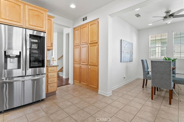 kitchen featuring stainless steel fridge, light brown cabinets, visible vents, and baseboards