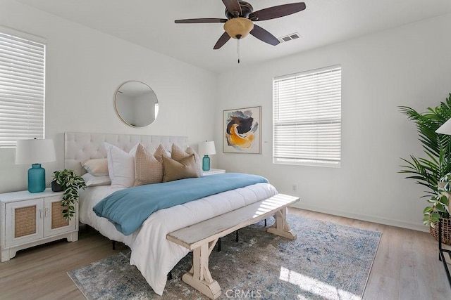 bedroom with light wood finished floors, baseboards, visible vents, and ceiling fan