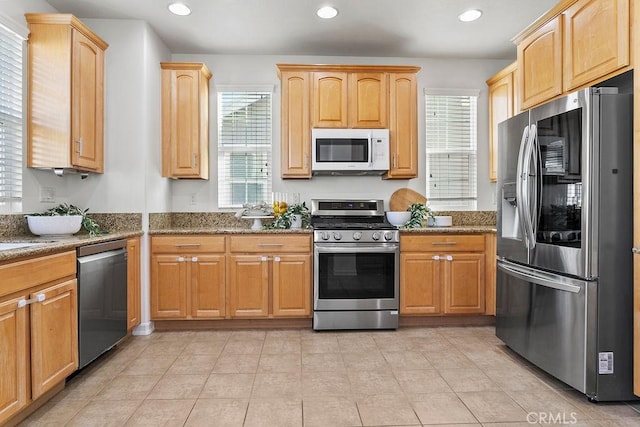 kitchen with stainless steel appliances, recessed lighting, stone counters, and light brown cabinetry