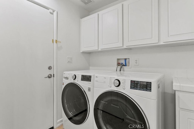 laundry area featuring visible vents, separate washer and dryer, and cabinet space