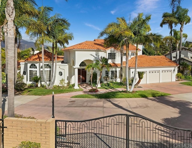 mediterranean / spanish-style house with an attached garage, a fenced front yard, a tile roof, and concrete driveway