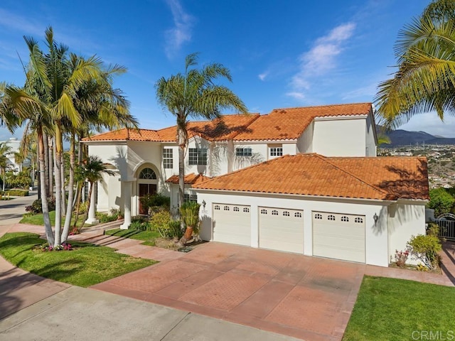 mediterranean / spanish house featuring a garage, a tile roof, concrete driveway, and stucco siding