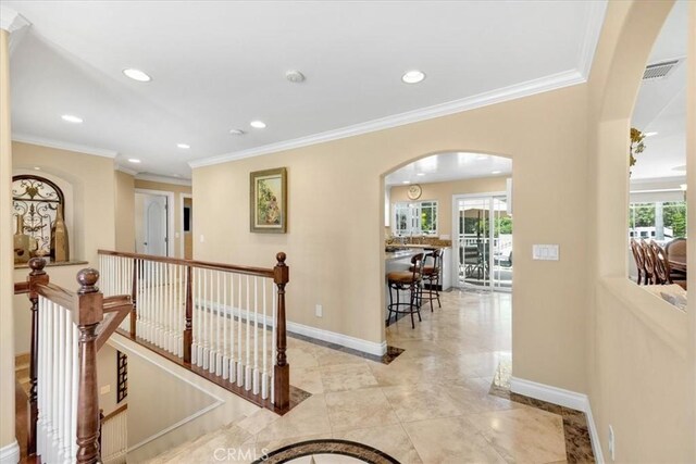 hall featuring arched walkways, an upstairs landing, plenty of natural light, and recessed lighting