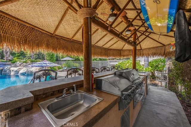 view of patio / terrace with fence, a gazebo, area for grilling, a sink, and a grill
