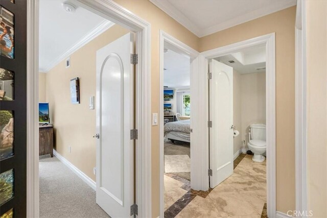 hall featuring baseboards, visible vents, and ornamental molding