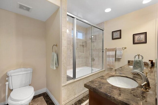 bathroom featuring visible vents, vanity, toilet, baseboards, and tiled shower / bath combo