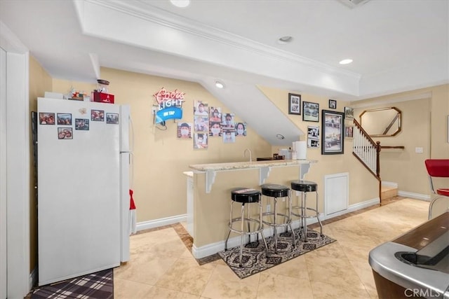 bar featuring crown molding, freestanding refrigerator, stairs, indoor wet bar, and a tray ceiling