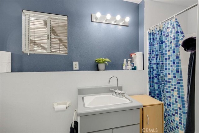bathroom featuring vanity, a textured wall, and a shower with curtain