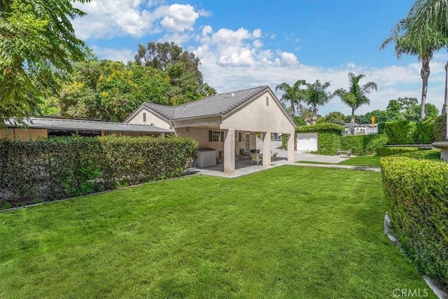 rear view of house featuring a patio area, stucco siding, and a yard