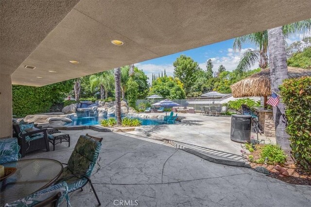 view of patio / terrace featuring visible vents, fence, outdoor dining space, and an outdoor pool